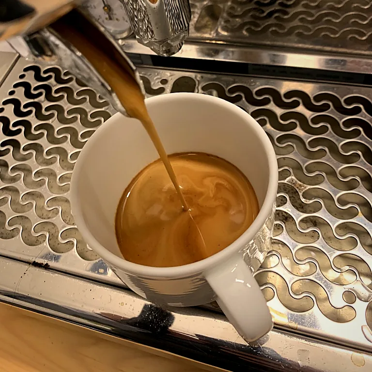 Frisch gebrühter Kaffee läuft an der Espressomaschine in eine weiße Tasse